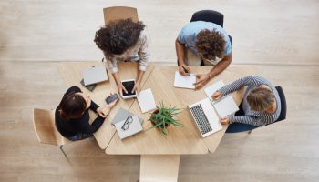 view-from-business-startup-teamwork-concept-startup-partners-sitting-coworking-space-talking-about-future-project-looking-through-examples-work-laptop-digital-tablet