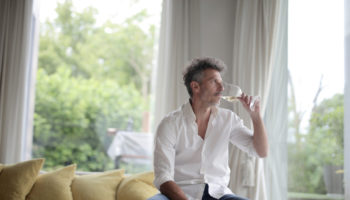 adult-man-drinking-glass-white-wine-sunlight-through-windows